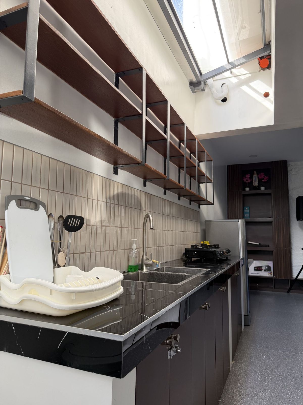 The kitchen counter with a sink, open shelving, stove and refrigerator