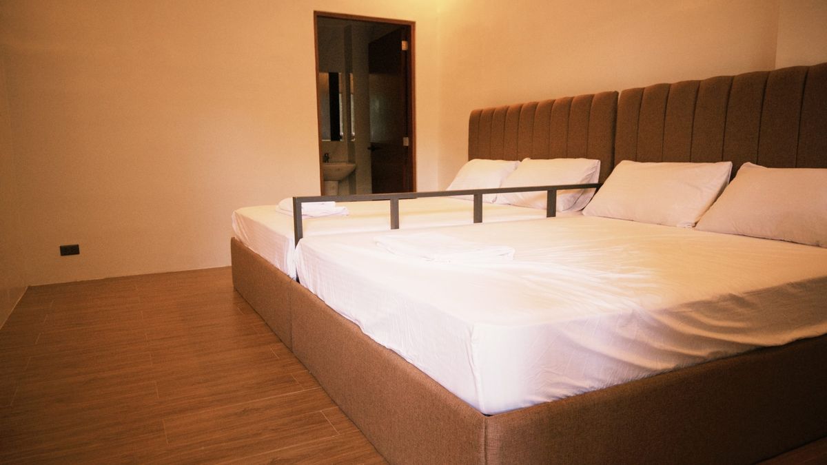 A double bed under warm amber light with the ensuite door standing open beside it